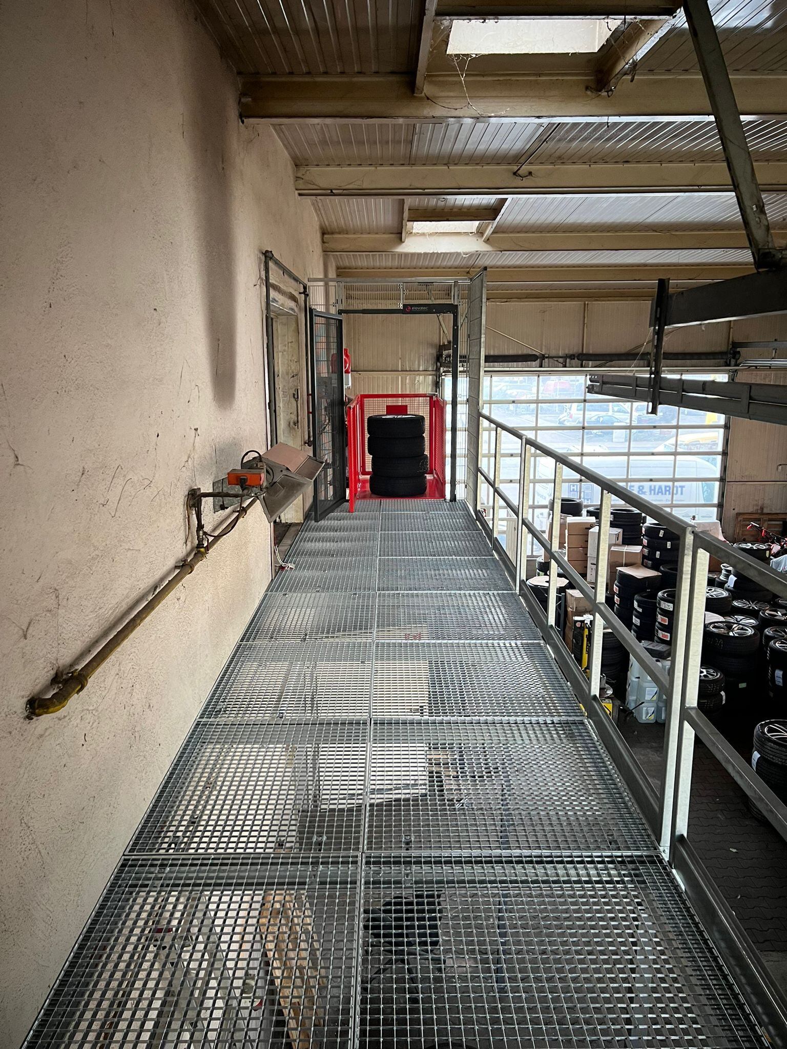 Warenlift an einer Stahlbühne mit Gitterboden